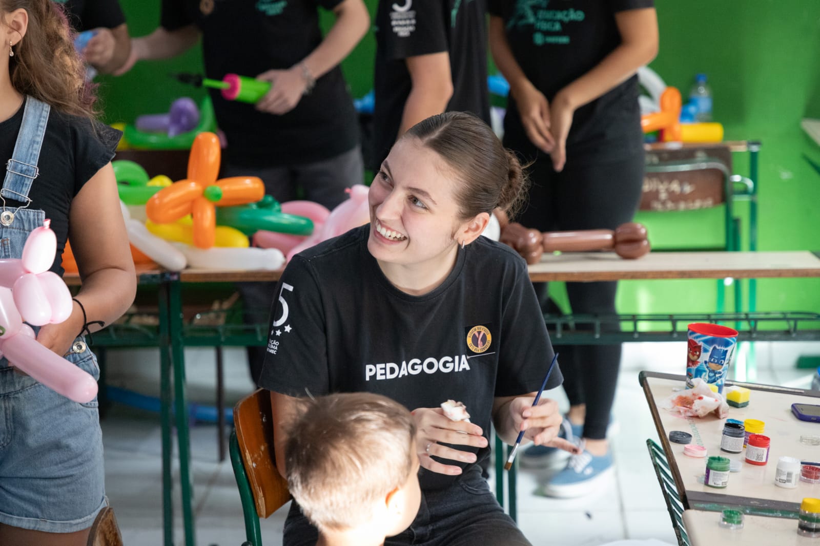Gabrieli sorrindo durante uma atividade de pintura com crianças